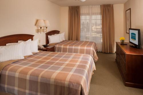 a hotel room with two beds and a television at Staybridge Suites Monterrey San Pedro by IHG in Monterrey