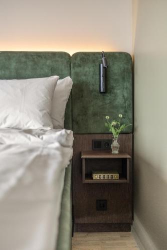 a bed with a green headboard and a night stand with a plant at Biologen Herdla in Askøy