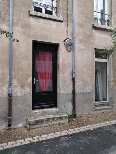 un bâtiment avec une porte noire et un rideau rouge dans l'établissement Studio Art Lumineux Evasion Sérénité Doué en Anjou, à Doué-la-Fontaine