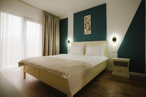 ein Schlafzimmer mit einem großen Bett mit einer blauen Wand in der Unterkunft Pensiunea Subcarpati in Jiblea Veche