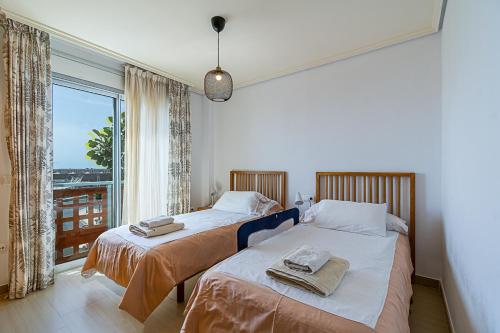 two beds in a room with a large window at Luxury Apartament Calle Pizarro La Tejita in La Mareta