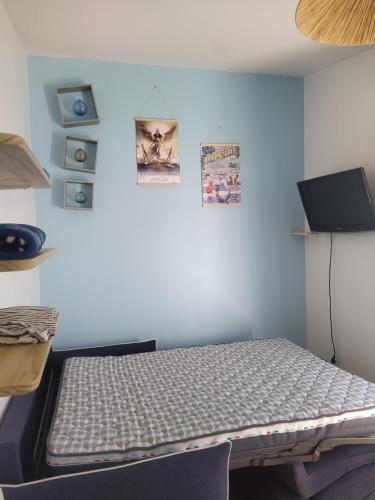 un lit dans une chambre avec un mur bleu dans l'établissement Le Palmier, à Les Sables-dʼOlonne