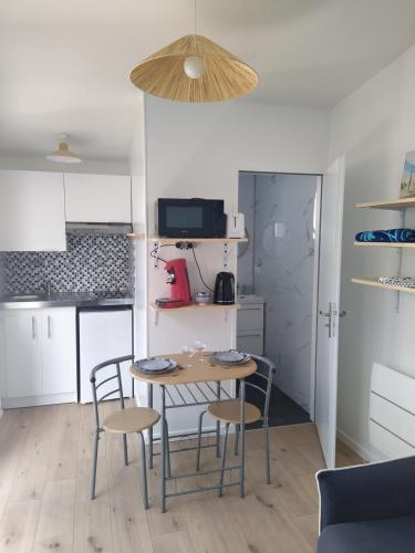 une cuisine avec une table et des chaises dans une pièce dans l'établissement Le Palmier, à Les Sables-dʼOlonne