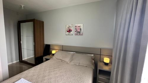 a small bedroom with a bed and a mirror at Apartamento Espetacular Melhor Localização Praia Navega BC e Itajaí in Navegantes
