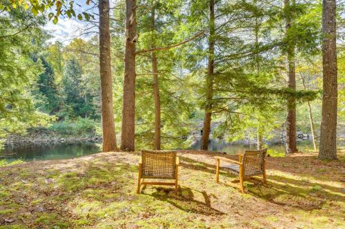 two benches sitting in the grass next to a river at Riverfront Hideaway in Keene Walk to Town! in Keene