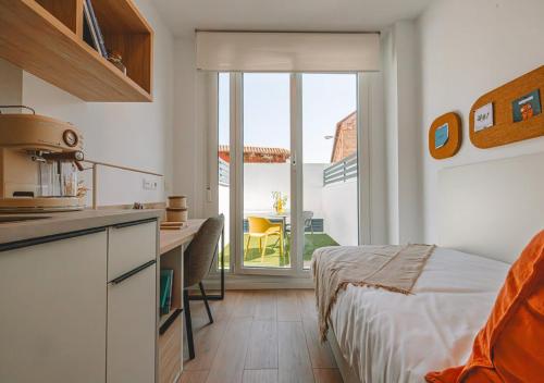 ein Schlafzimmer mit einem Bett und eine Küche mit einem Balkon in der Unterkunft Vibe Stay Granada in Granada