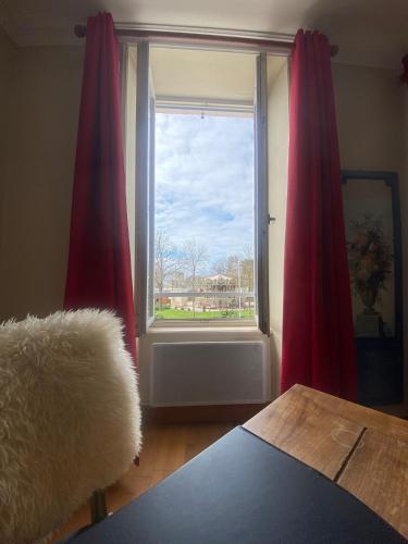 - un salon avec une fenêtre dotée de rideaux rouges dans l'établissement L'Appart Du Vieux Port, à La Rochelle