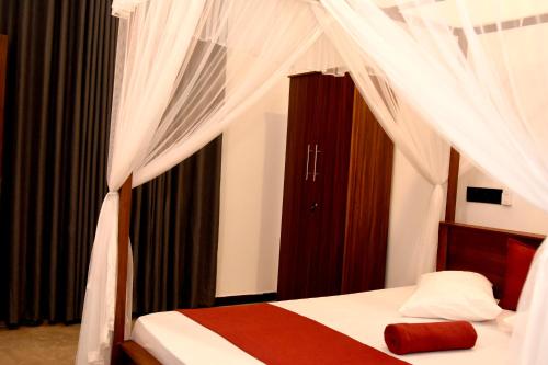 a bedroom with a bed with a canopy and curtains at Chathu Villa in Walgama South