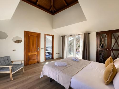 a bedroom with a large white bed and a chair at Casa Dorada by Best Holidays Fuerteventura in Corralejo