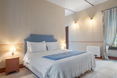 a bedroom with a white bed with a blue headboard and a window at Marchesi Incisa Winery Lodge in Rocchetta Tanaro