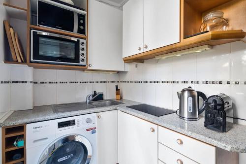 une cuisine avec un lave-linge et un micro-ondes dans l'établissement Charming flat in old Paris, à Paris