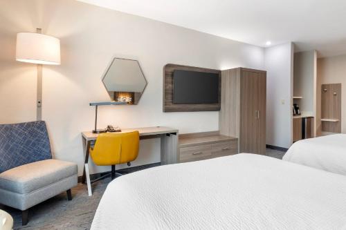 a hotel room with a bed and a desk and a tv at Holiday Inn Express Hotel and Suites Alice by IHG in Alice