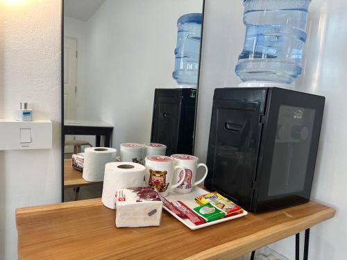 a table with cups and a television on top of it at The White Den Sukhumvit 44 in Bangkok