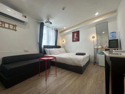 a small room with a bed and a couch at The White Den Sukhumvit 44 in Bangkok