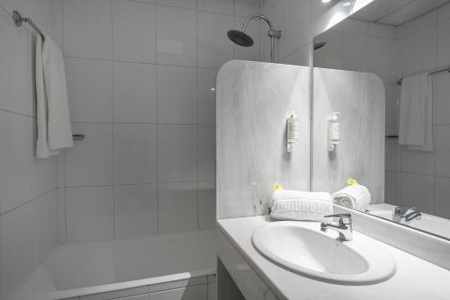 a white bathroom with a sink and a shower at Hotel Estacão - Braga in Braga