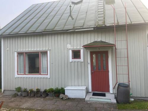 a small white house with a red door and windows at 2 bedroom house central Parainen in Pargas
