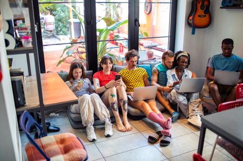 a group of people sitting on a couch looking at their cell phones at Good People Design Hostel in Belgrade