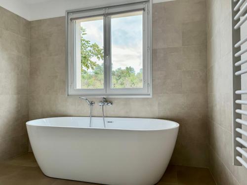 a bath tub in a bathroom with a window at Appartement Mare è Machja avec piscine et vue mer in Sari Solenzara