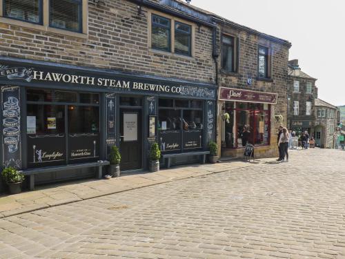 a brick building with a sign on it on a street at The Snug on the Cobbles in Keighley