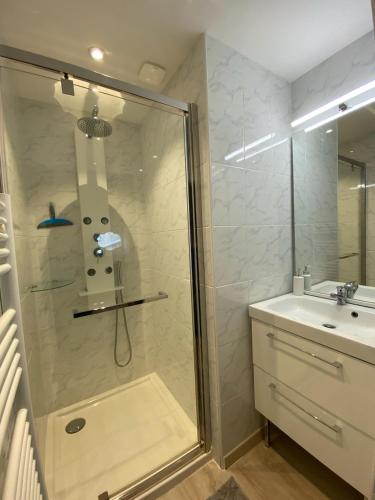 une douche avec une porte vitrée à côté d'un lavabo dans l'établissement Maison Centre bourg, à Villedoux