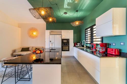a kitchen with white cabinets and a green ceiling at L'Anse Étoilée - Grande Anse in Petite Île
