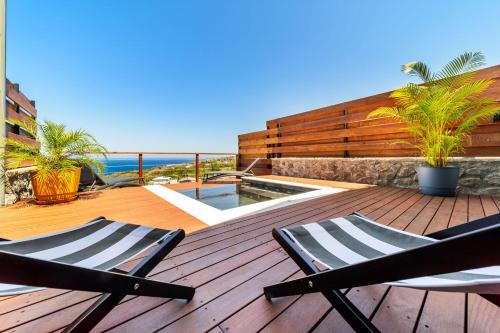 two chairs on a wooden deck with a swimming pool at L'Anse Étoilée - Grande Anse in Petite Île