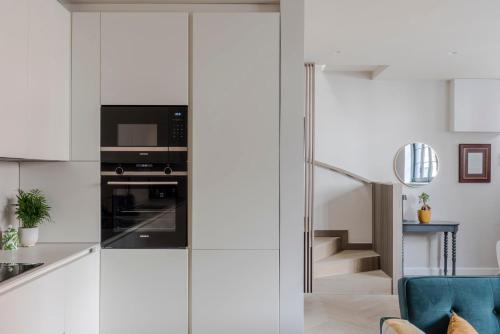 a kitchen with white cabinets and a blue chair at Stunning 2-Bed Mews House with AC near Regent's Park in London