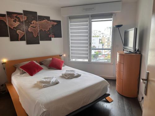 - une chambre avec un lit doté d'oreillers rouges et une télévision dans l'établissement Issy - les jardins du séminaire, à Issy-les-Moulineaux