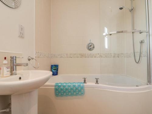 a white bathroom with a sink and a tub and a sink at Spindrift in Reighton