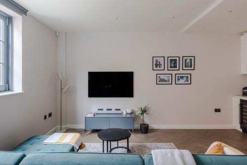 a living room with a blue couch and a tv at Stunning 2-Bed Mews House with AC near Regent's Park in London