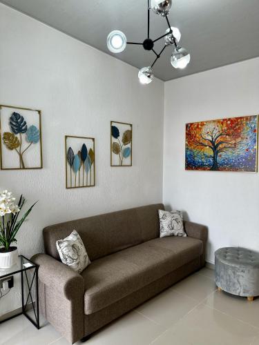 a living room with a couch and some paintings at Casa Los Ausoles con Jacuzzi in Ahuachapán
