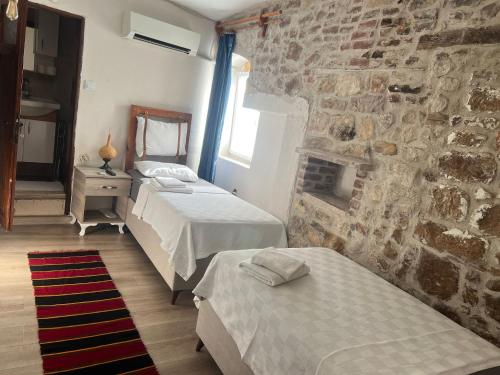 a bedroom with two beds and a stone wall at şekercigiller in Ayvalık
