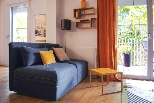 a blue couch in a living room with a window at SweetHomeVersailles 10mn walk from Palace in Versailles