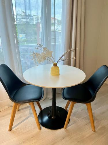 d'une table et de deux chaises avec un vase. dans l'établissement Le SerenityAppart Suresnes, à Suresnes