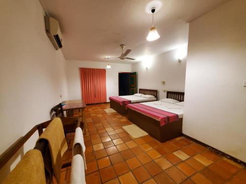 a hotel room with two beds and a balcony at Clay Hut Village in Polonnaruwa