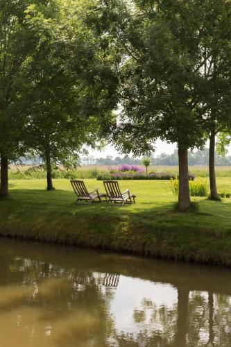 two chairs sitting next to a river with trees at Landgoedlogies Pábema in Zuidhorn