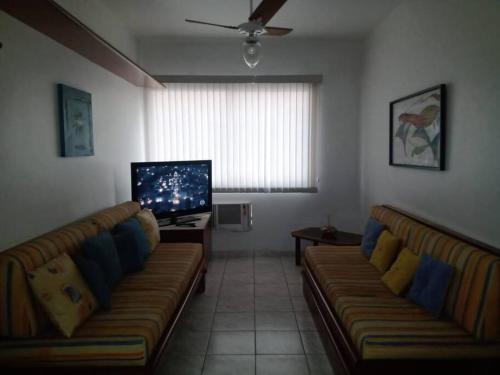 a living room with two couches and a flat screen tv at Espaço Aconchegante no coração da Praia da Enseada in Guarujá
