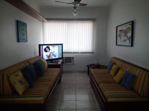 a living room with two couches and a flat screen tv at Espaço Aconchegante no coração da Praia da Enseada in Guarujá