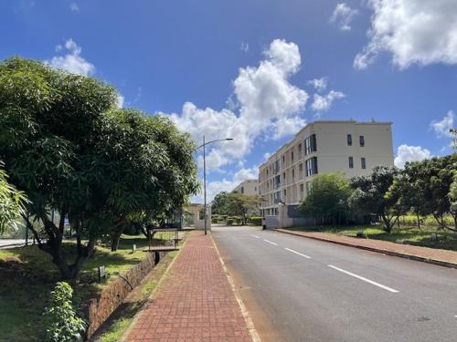 an empty street with a building and a tree at JF Skyline Apartments in Baie du Tombeau