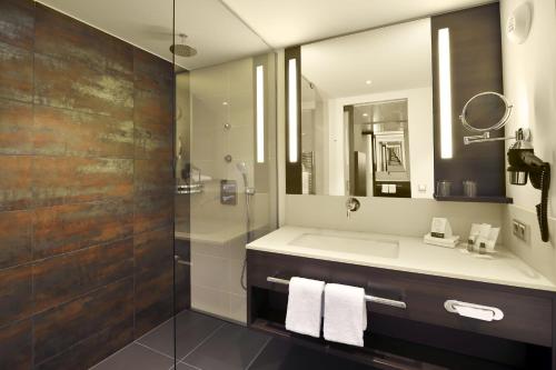 a bathroom with a sink and a shower with a mirror at Atlantic Congress Hotel Essen in Essen