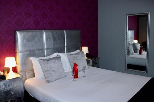 a bed with two wine glasses and a mirror at V E R O N E - Rooms & Suites - Liège - Rocourt in Liège