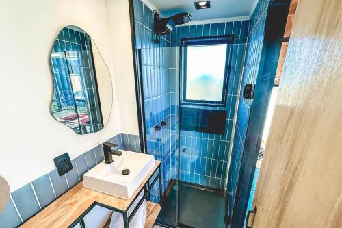 Un baño con azulejos azules, lavabo y espejo. en Cabana charmosa com vista deslumbrante!, en Morungaba