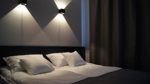 a bedroom with a bed with two pillows and two lights at Art Apartment Szczecin in Szczecin