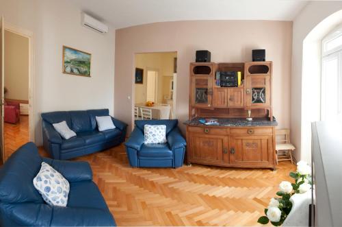 a living room with blue couches and a wooden cabinet at Gianina Apartment in Split