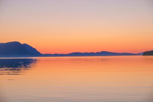 a sunset over the water with mountains in the background at Lyngen Vista - Arctic Luxury in Hamnnes