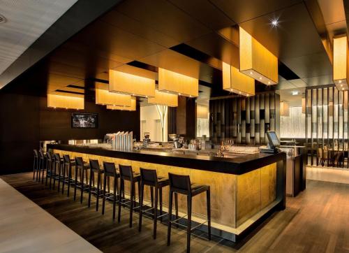 a restaurant with a bar with chairs and lights at Atlantic Congress Hotel Essen in Essen