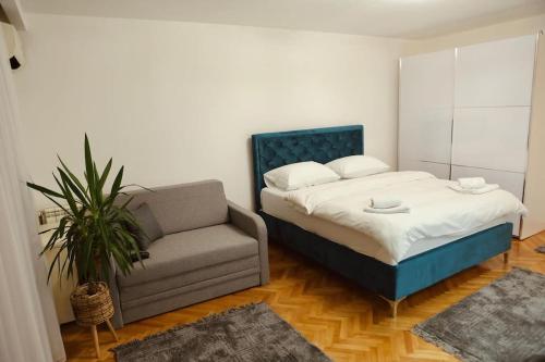 a bedroom with a bed and a couch and a chair at Apartman Čaršija in Novi Pazar