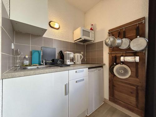 une petite cuisine avec des armoires blanches et un évier dans l'établissement Studio cosy proche pistes avec balcon et parking, 4 couchages - FR-1-330F-241, à La Salle Les Alpes