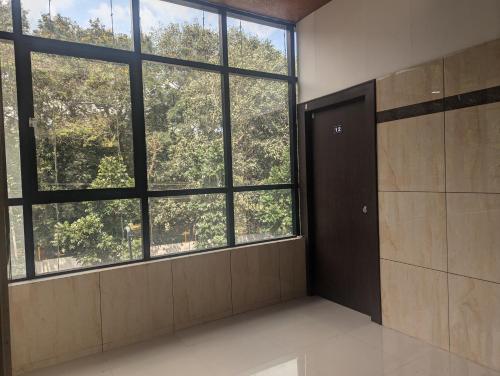 an empty room with a door and large windows at Govinda Krishna Comforts in Mysore