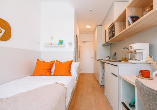 ein kleines Schlafzimmer mit orangefarbenen Kissen auf einem Bett in der Unterkunft Vibe Stay Granada in Granada